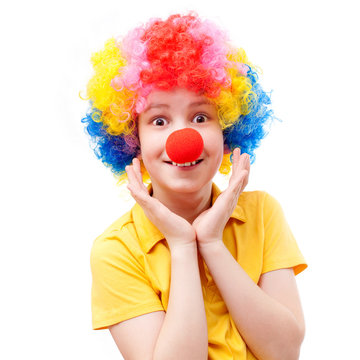 A surprised boy with a red clown nose and bright wig