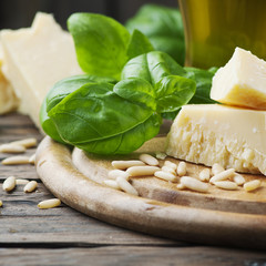Basil, cheese, pine and olive oil on the wooden table