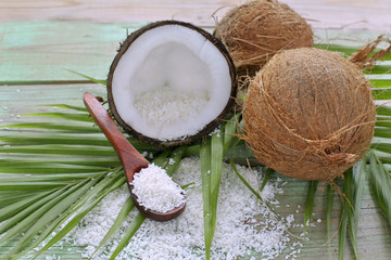 
  coconuts with flakes and palm leaves on wooden background 