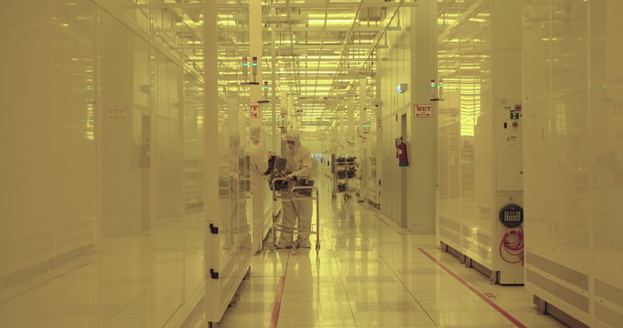Workers in clean suits on the production floor of a semiconductor fabrication facility