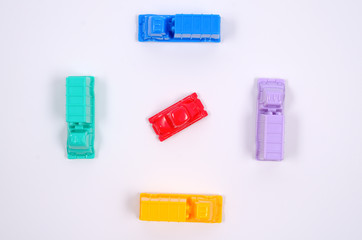 Colorful plastic toy cars on a white background. Many cars surrounded one car. Dense urban city traffic. Concept. Close up view, flat lay. 