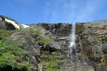 Fototapeta na wymiar Small waterfall over a rocky cliff, subarctic mountains, Swedish Lapland