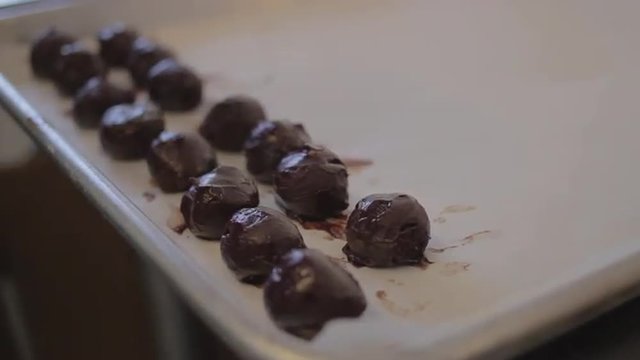 Close up of chocolate mousse truffles being placed onto a cookie sheet