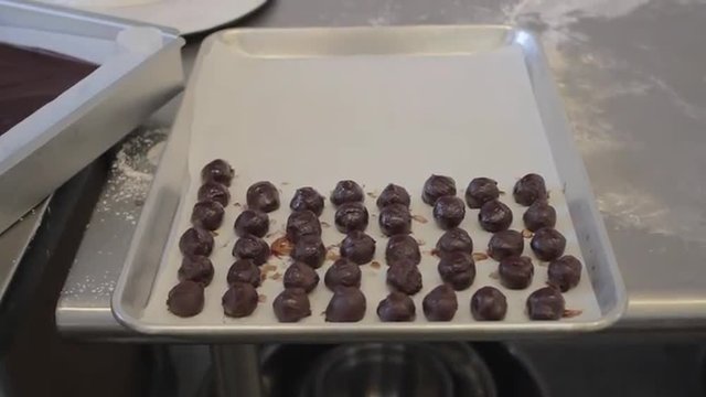Wide shot of chocolate mousse truffles being placed onto a cookie sheet