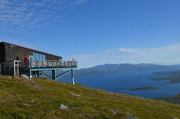 Wooden house of ski lift on top of mountain slope overlooking lake Torneträsk in summer, Abisko, Swedish Lapland