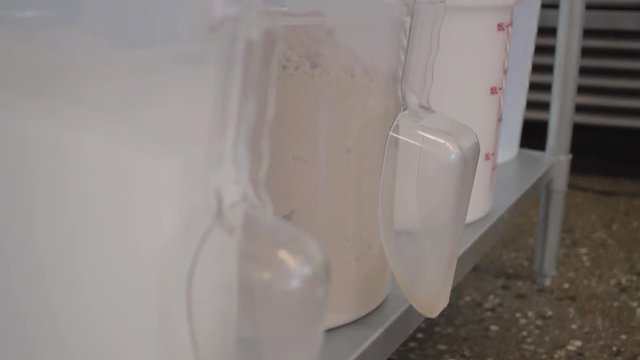 Pan up of large clear white bins holding sugar and flour