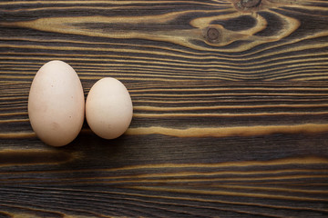 Two different eggs at the wooden background