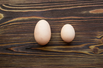 Two different eggs at the wooden background