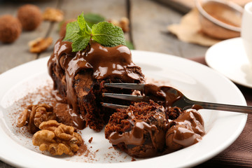 A piece of chocolate cake with walnut and mint on the table, close-up