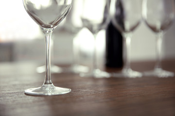 Empty wine glasses with bottle on wooden table against blurred background