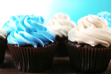 Chocolate cupcakes on wooden table in front of blue background