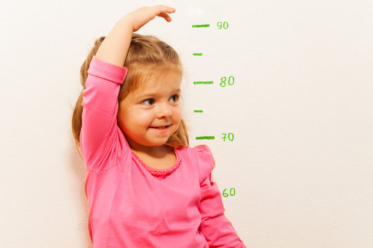 Height measurement by little girl at the wall