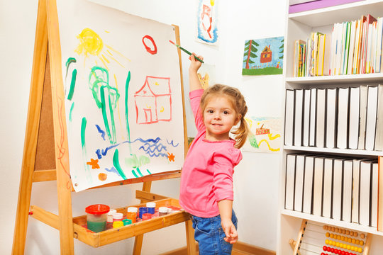 Girl painting with green brush at the easel