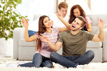 Teenager couple listening to music with earphones in living room