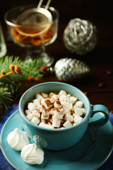 Mug of hot chocolate with marshmallows, fir tree branch on wooden background