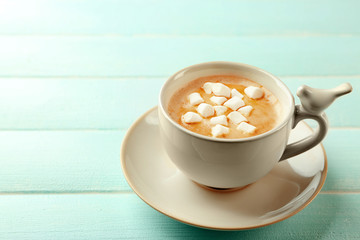 Cup of hot cacao with marshmallow on blue table