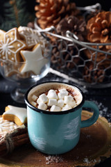 Mug of hot cacao with marshmallow and cookies on black table