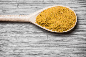Curry powder on wooden spoon background.