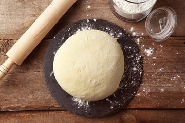 Fototapeta na wymiar Fresh prepared dough on a wooden board, close up