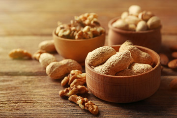 Pistachios, almonds, peanuts and walnut kernels in the wooden bowls on the table, close-up