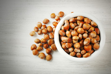 Hazelnuts in the bowl on white wooden background