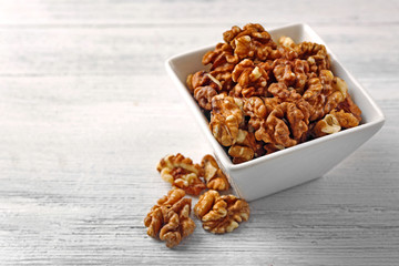 Walnut kernels in the bowl on white wooden background