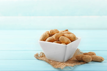 Peanuts in the bowl on blue wooden background