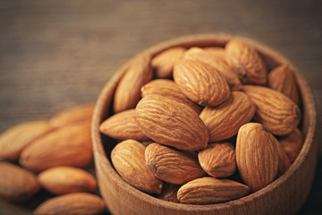 Almonds in the wooden bowl on the table, close-up