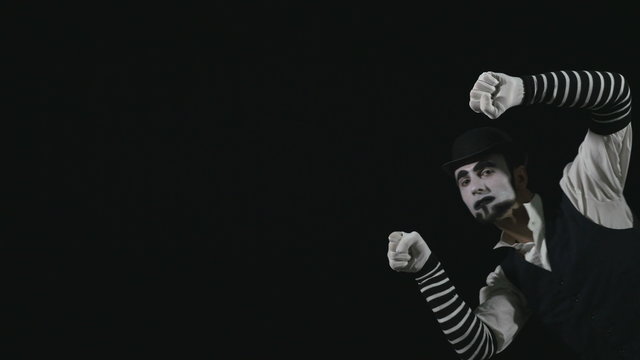 Young funny mime performing a invisible wall act