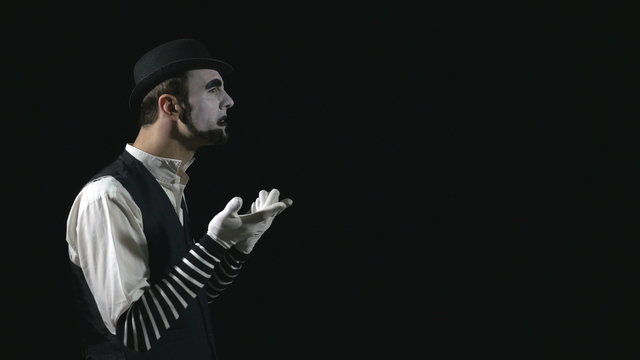 Young funny mime showing and pointing at something and explaining