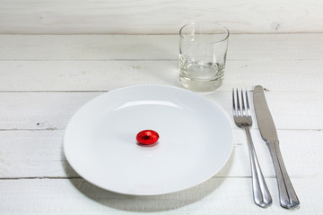 white plate with a small red easter egg,  knife, fork and drinki