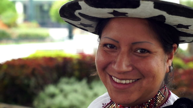 Close up side portrait shot of an indigenous Saraguro woman smiling and wearing traditional dress in the province of Loja and the country of Ecuador.