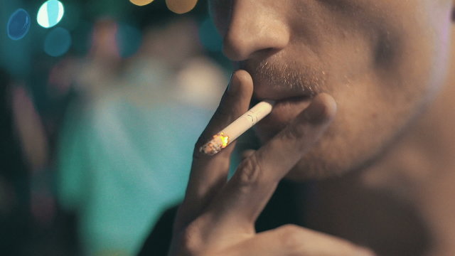 Man smoking a cigarette at night club, close up, slow motion, low light