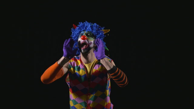 Young funny clown shouting and using a megaphone