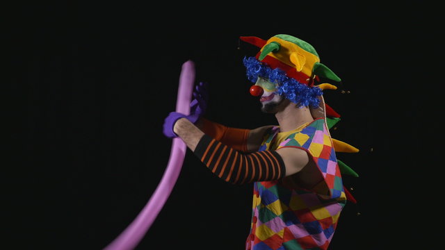 Young funny clown making a poodle from a balloon