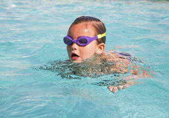 Young girl wearing goggles in swimming pool