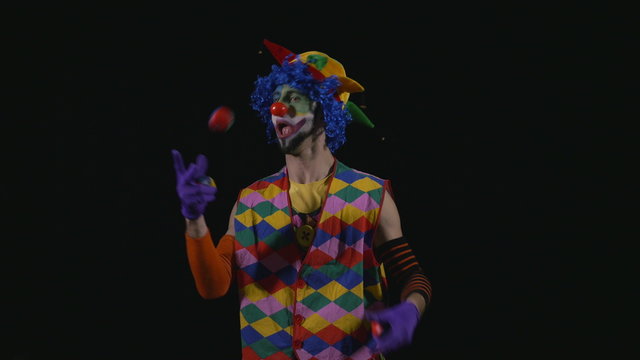 Young funny hilarious clown juggling