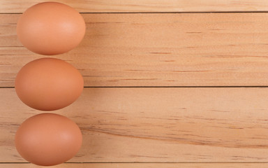 Row of Three Brown Eggs on a Wooden Surface