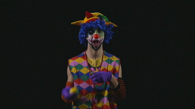 Young hilarious clown juggling in slow motion