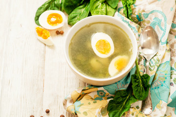 
healthy lunch , green soup with sorrel or spinach , boiled egg and spices on wooden background