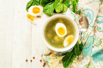 
healthy lunch , green soup with sorrel or spinach , boiled egg and spices on wooden background