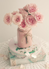 Roses in a pink vase with skeleton key over book with vintage dust jacket