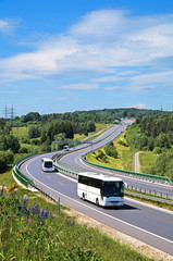 Buses on the highway with electronic toll gates in a countryside. The view from above. Sunny summer day with blue skies and white clouds.