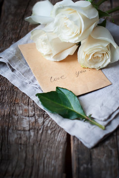 Message Love You on old Paper and bouquet of White Roses