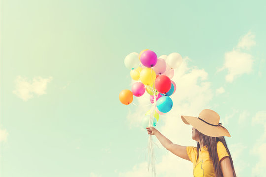 Happy young woman holding colorful balloons with floating, concept of relax in summer - vintage color tone