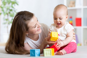 Mother and baby girl playing with developmental toys in living room