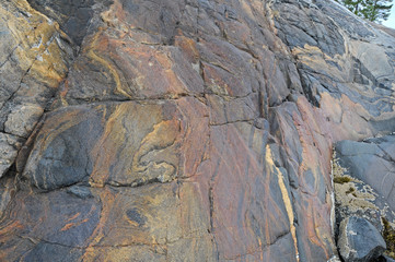 Granite rocks atop million year old igneous volcanic rock at sunset during low tide on the white sea coast showing the erosion of the rock due to waves and tides.