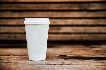 Paper coffee cup from coffee shop on wooden background