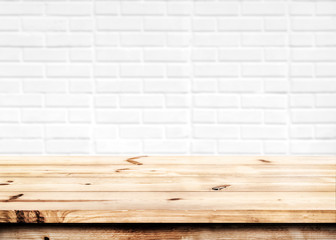 Empty wooden table for product placement or montage with focus to the table top in the foreground, with white brick wall background.