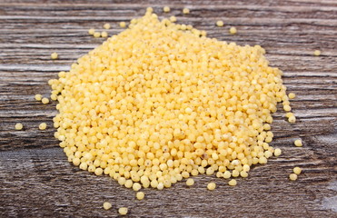 Heap of millet groats on wooden background